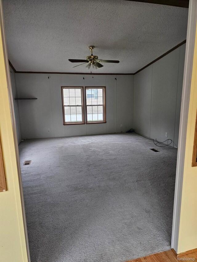 73 Grey Fox Ct, Grand Blanc, MI 48439 - empty room featuring light carpet, a ceiling fan, a textured ceiling, crown molding, and a decorative wall