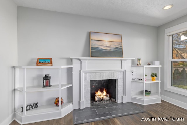 living area featuring a textured ceiling, wood finished floors, recessed lighting, a fireplace, and baseboards
