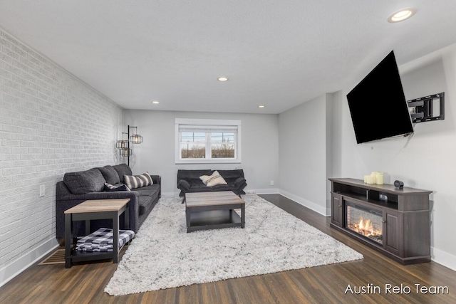 living area featuring dark wood-style floors and brick wall