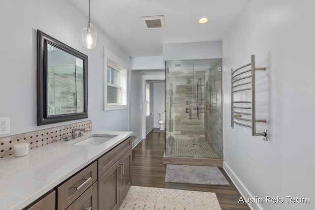 full bath with visible vents, wood finished floors, a shower stall, baseboards, and vanity
