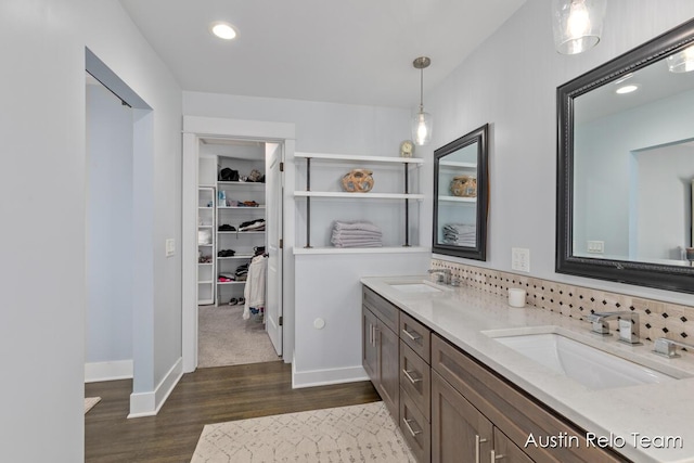 bathroom with a sink, baseboards, wood finished floors, and double vanity