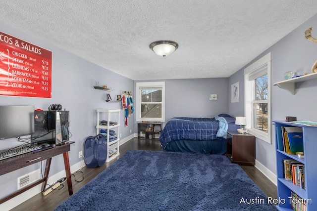 bedroom featuring visible vents, baseboards, a textured ceiling, and wood finished floors