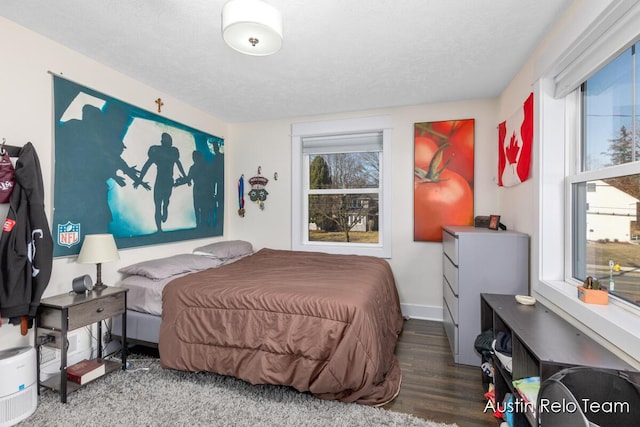 bedroom with a textured ceiling, baseboards, and wood finished floors
