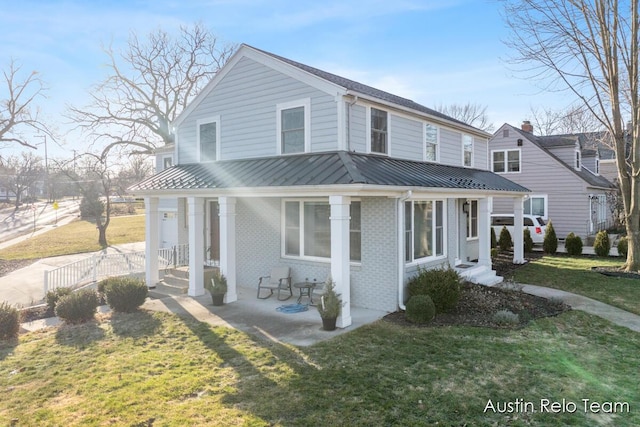 view of front of house with a standing seam roof, a front lawn, brick siding, and metal roof