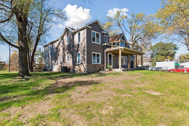 rear view of house featuring central AC unit and a lawn