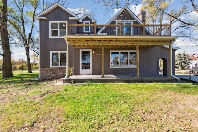 view of front of home with a balcony, a chimney, and a front yard