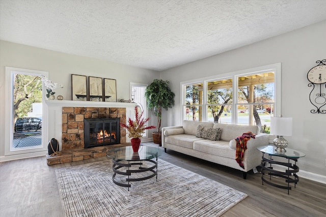 living area with baseboards, a textured ceiling, wood finished floors, and a fireplace