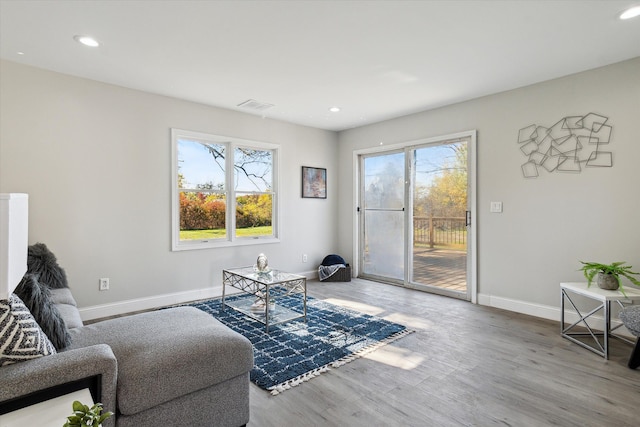 sitting room with wood finished floors, a healthy amount of sunlight, visible vents, and baseboards