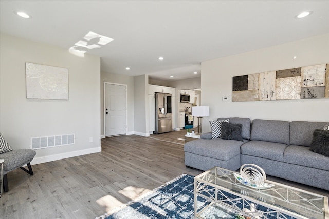 living room featuring recessed lighting, visible vents, baseboards, and wood finished floors