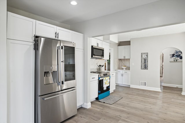 kitchen with visible vents, arched walkways, appliances with stainless steel finishes, and white cabinets