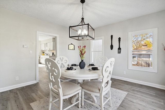 dining space featuring an inviting chandelier, wood finished floors, and baseboards