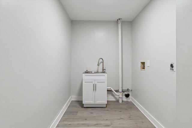 laundry area with light wood finished floors, baseboards, washer hookup, cabinet space, and a sink