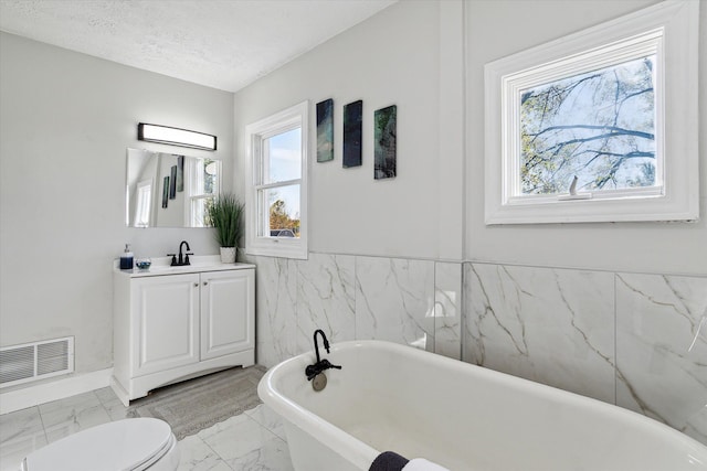 full bath with vanity, visible vents, a soaking tub, a textured ceiling, and marble finish floor