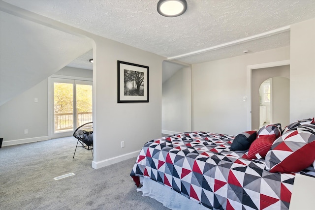 bedroom with visible vents, a textured ceiling, arched walkways, carpet floors, and baseboards
