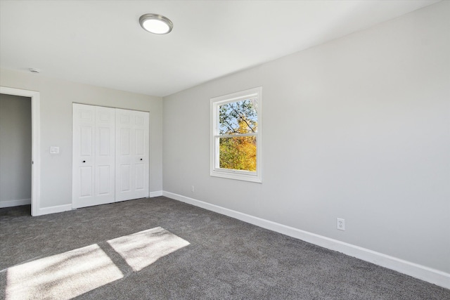 unfurnished bedroom featuring a closet, baseboards, and dark carpet