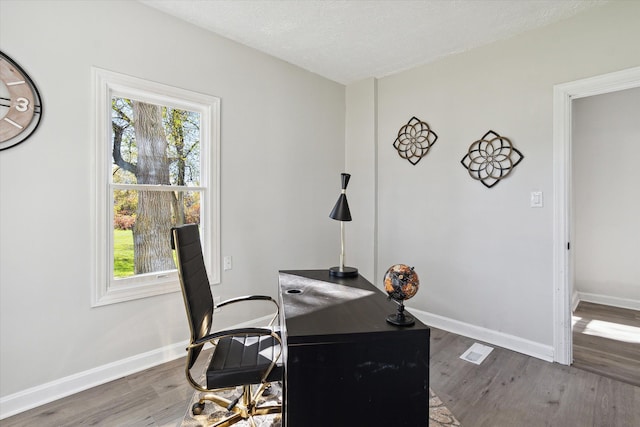 home office with wood finished floors, a healthy amount of sunlight, and baseboards