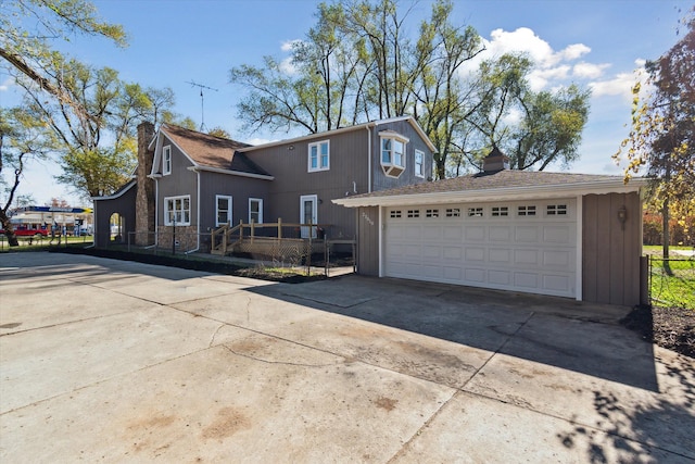 view of front of house with an outdoor structure, fence, a detached garage, and a chimney