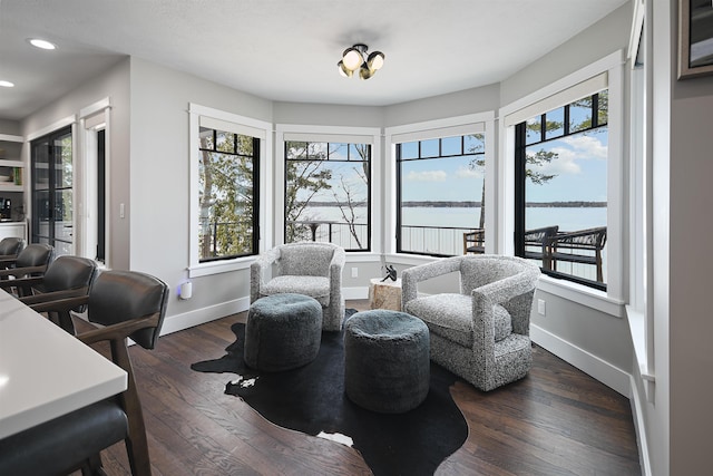 living area featuring recessed lighting, a water view, baseboards, and hardwood / wood-style flooring