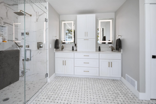 full bath featuring a marble finish shower, visible vents, double vanity, and a sink