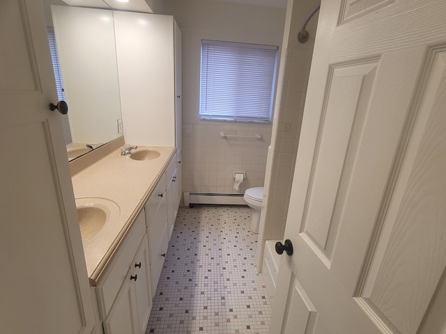 full bath featuring toilet, a sink, tile walls, double vanity, and baseboard heating