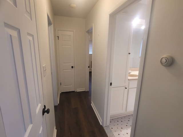 corridor featuring baseboards and wood finished floors
