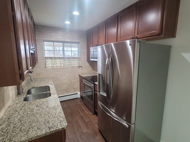 kitchen featuring a sink, backsplash, a baseboard heating unit, stainless steel appliances, and dark wood-style flooring
