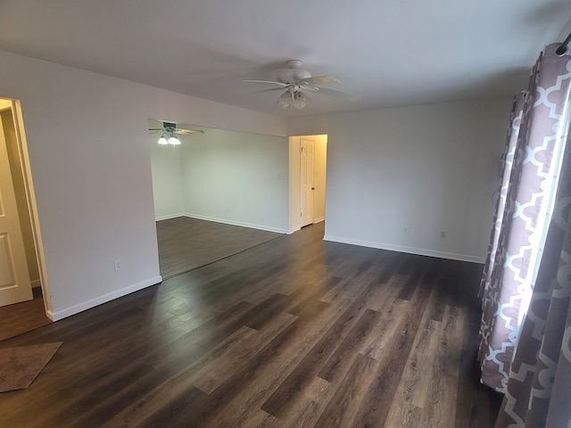 empty room featuring baseboards, a ceiling fan, and dark wood-style flooring