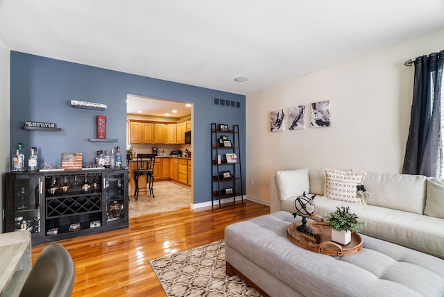 living area featuring light wood-style floors, baseboards, recessed lighting, and visible vents