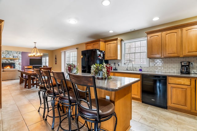 kitchen featuring a sink, a breakfast bar area, black appliances, and a healthy amount of sunlight