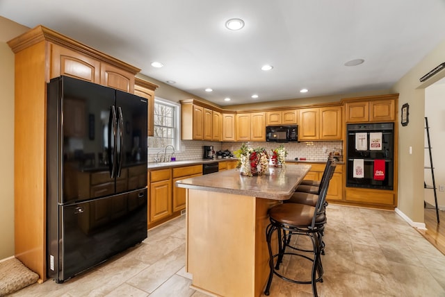 kitchen with a breakfast bar, a sink, backsplash, a kitchen island, and black appliances