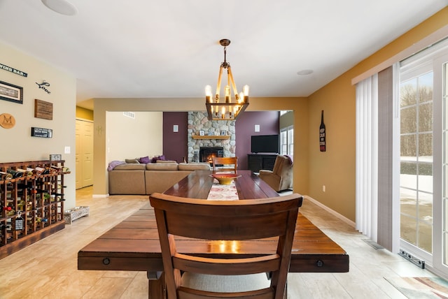 dining room with light tile patterned floors, baseboards, a fireplace, and a chandelier