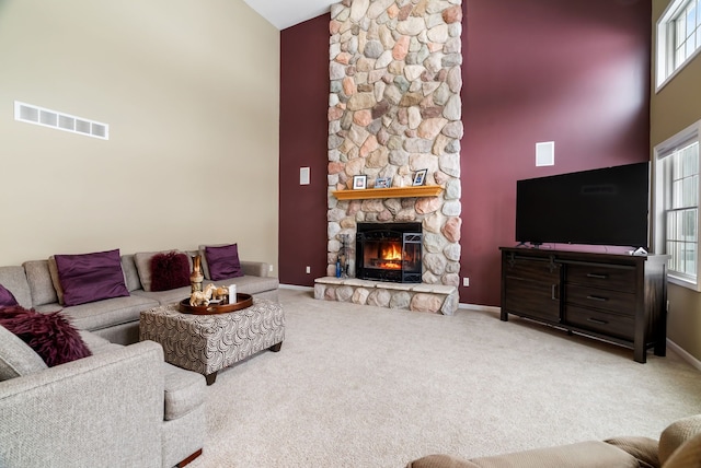 carpeted living room with high vaulted ceiling, baseboards, a fireplace, and visible vents