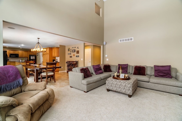 living room with visible vents, a high ceiling, a notable chandelier, and light carpet