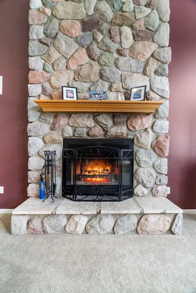 interior details featuring a stone fireplace, baseboards, and carpet floors