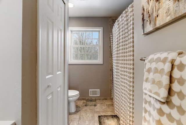 full bathroom with baseboards, toilet, and visible vents