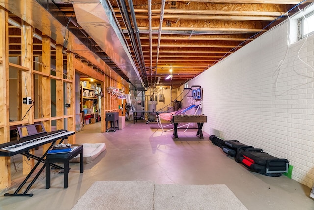 recreation room with brick wall and finished concrete floors
