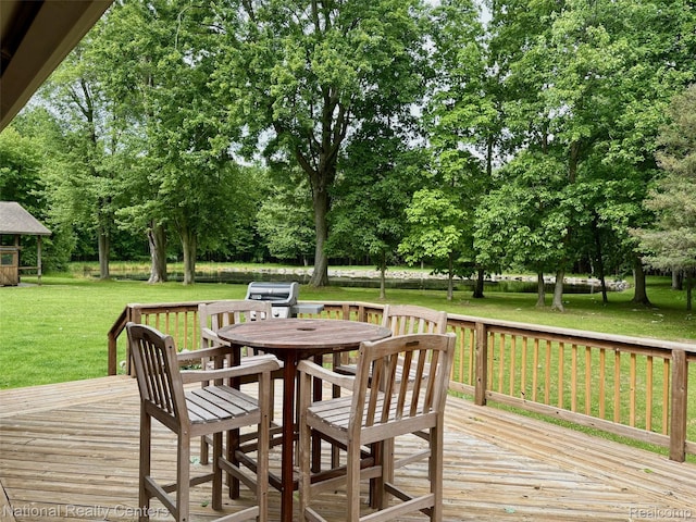 9247 Schrepfer Rd, Howell, MI 48855 - deck with outdoor dining space, a yard, view of wooded area, and a grill