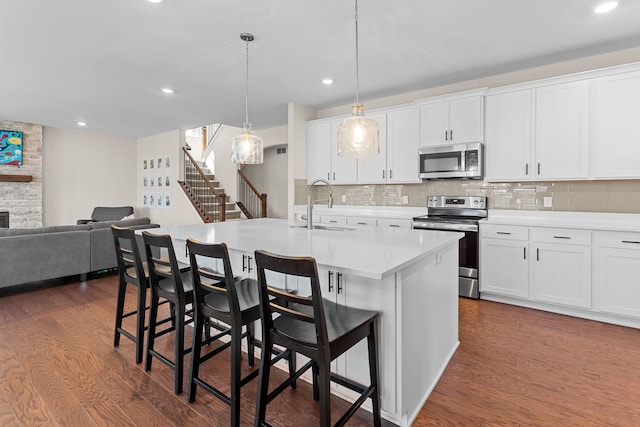 kitchen featuring a sink, backsplash, appliances with stainless steel finishes, and dark wood-style flooring