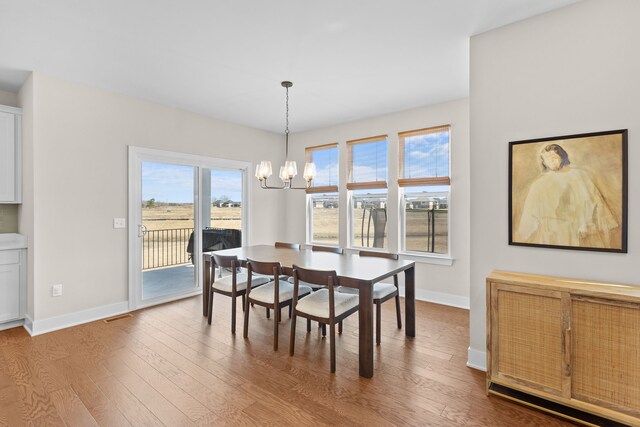 dining room featuring visible vents, baseboards, an inviting chandelier, and wood finished floors