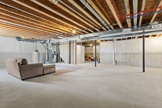 unfinished basement featuring water heater, visible vents, and heating unit
