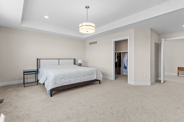 carpeted bedroom featuring baseboards, visible vents, a tray ceiling, recessed lighting, and a walk in closet