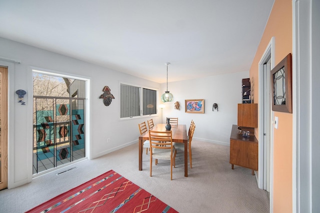 dining room featuring visible vents, light carpet, and baseboards