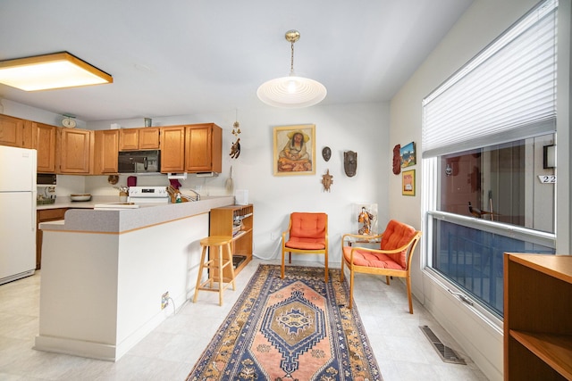 kitchen featuring visible vents, black microwave, light countertops, electric stove, and freestanding refrigerator