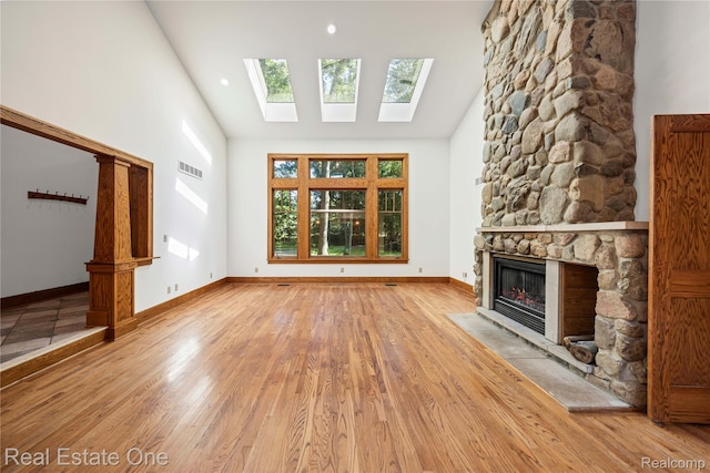 28190 Wildwood Trl, Farmington Hills, MI 48336 - unfurnished living room with a stone fireplace, wood finished floors, a skylight, and high vaulted ceiling