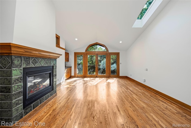28190 Wildwood Trl, Farmington Hills, MI 48336 - unfurnished living room featuring a tiled fireplace, light wood-style floors, a skylight, recessed lighting, and high vaulted ceiling