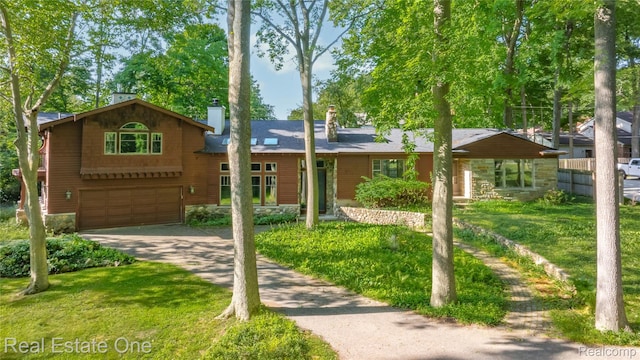 28190 Wildwood Trl, Farmington Hills, MI 48336 - view of front facade featuring a chimney, concrete driveway, an attached garage, a front yard, and stone siding