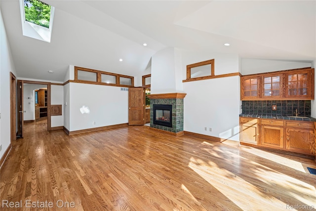 28190 Wildwood Trl, Farmington Hills, MI 48336 - unfurnished living room featuring high vaulted ceiling, a skylight, a fireplace, light wood finished floors, and recessed lighting