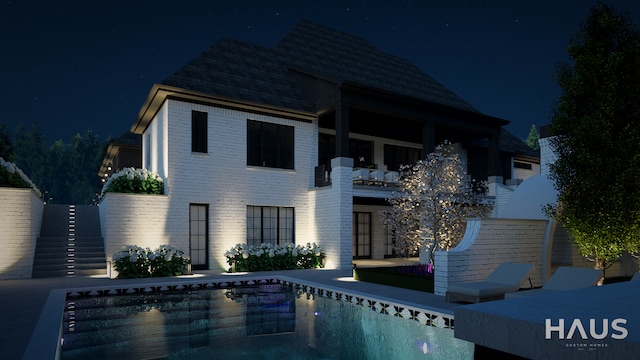 1644 Vista Dr, Oakland, MI 48363 - back of house at night featuring an outdoor pool, stairway, and brick siding