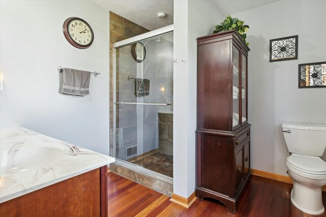 full bath with vanity, wood finished floors, baseboards, a shower stall, and toilet