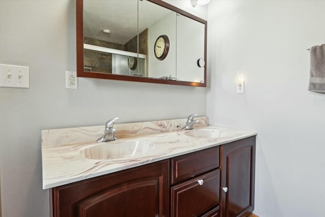 bathroom with double vanity, a stall shower, and a sink